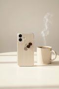 Phone with a textured case next to a steaming cup of coffee on a neutral background